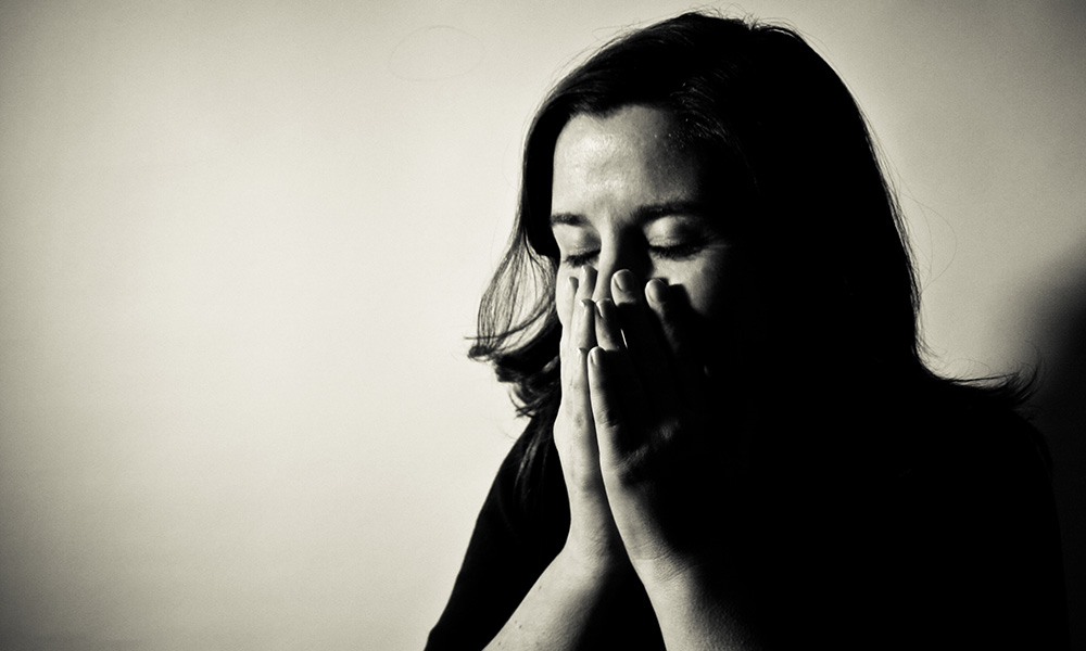 Stressed woman holding her hands to her face.