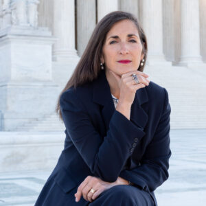 Kate Cerulli sitting on outdoor steps with her hand on her chin.